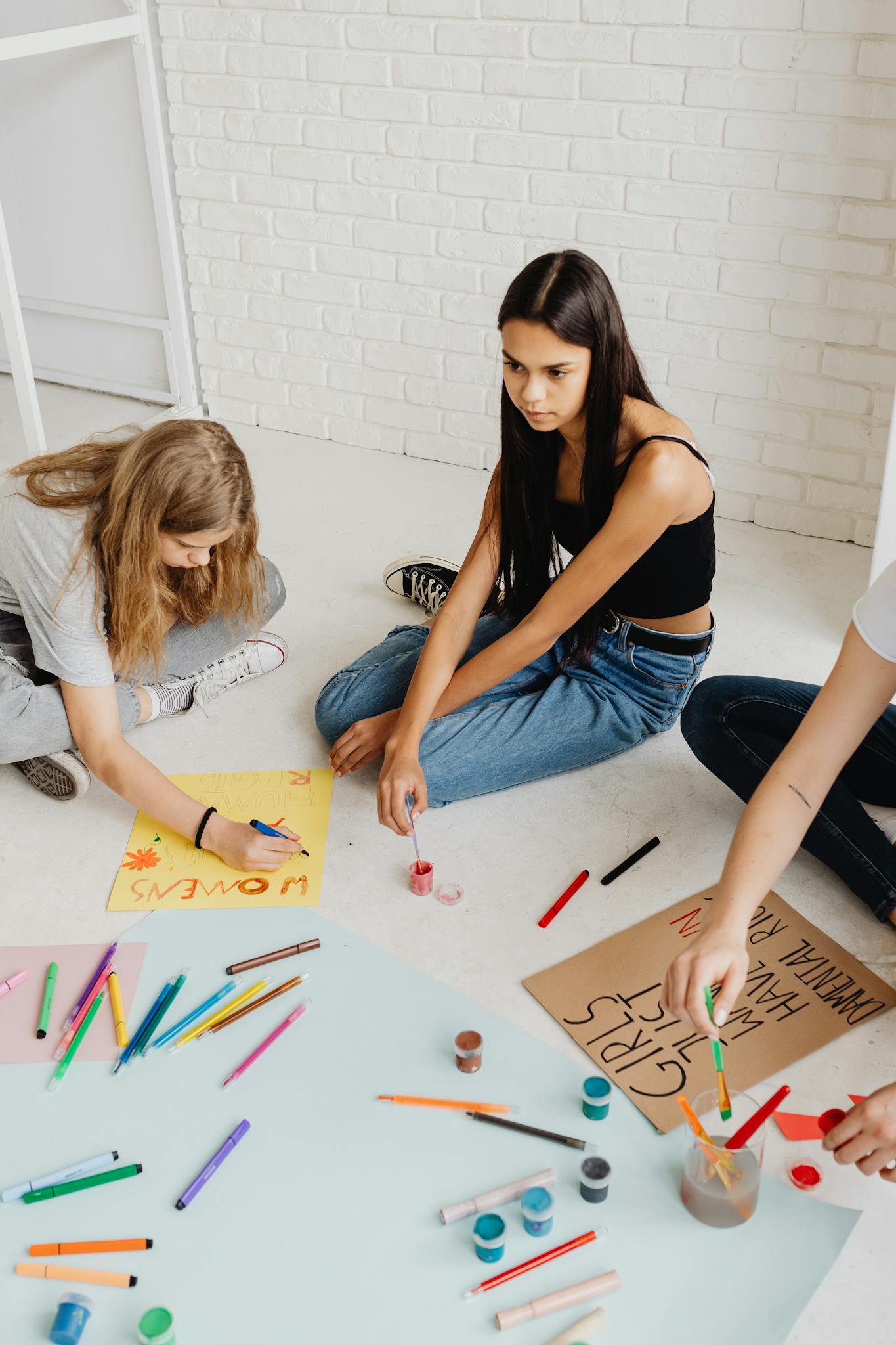 Teenagers engage in creative poster painting session promoting social awareness indoors.